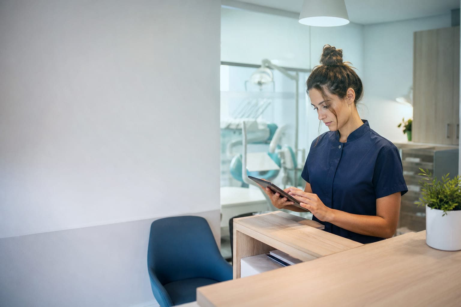 La recepcionista de una clínica dental revisa en una tablet las reseñas recientes del centro.