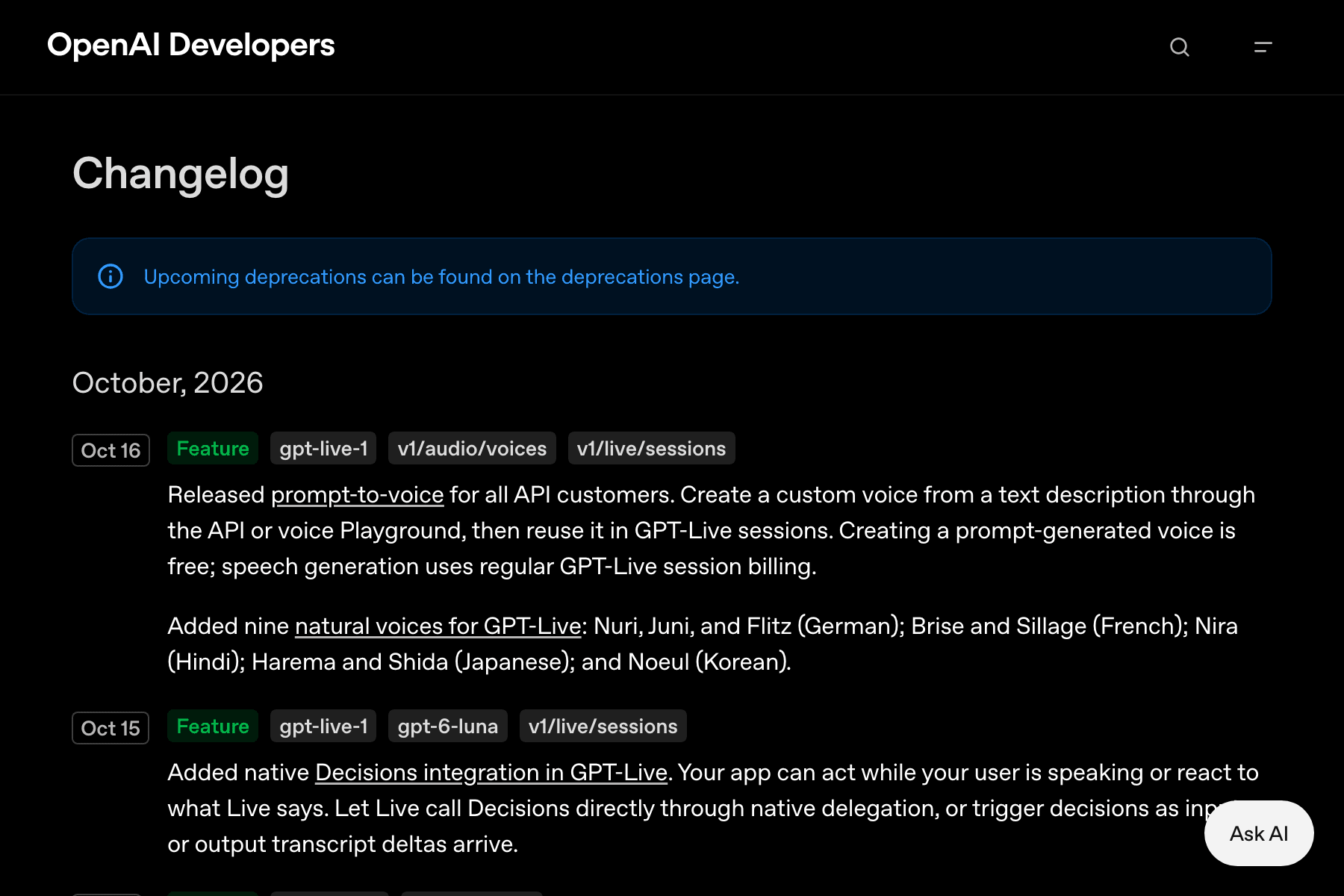 Captura de una página web de fondo negro. Arriba a la izquierda, el rótulo «OpenAI Developers» en blanco y, a la derecha, una lupa y un icono de menú. Debajo, el título «Changelog» en letra grande y un recuadro azul oscuro con un icono de información y el texto «Upcoming deprecations can be found on the deprecations page.». Sigue el encabezado «October, 2026» y, bajo él, dos entradas. La primera lleva a la izquierda la etiqueta «Oct 16» en un recuadro gris y, a su lado, cuatro etiquetas más: «Feature» en verde, «gpt-live-1», «v1/audio/voices» y «v1/live/sessions»; su texto anuncia el lanzamiento de prompt-to-voice para todos los clientes de la API y, en un segundo párrafo, nueve voces nuevas con sus idiomas entre paréntesis: Nuri, Juni y Flitz (alemán), Brise y Sillage (francés), Nira (hindi), Harema y Shida (japonés) y Noeul (coreano). La segunda entrada lleva la etiqueta «Oct 15» con «Feature», «gpt-live-1», «gpt-6-luna» y «v1/live/sessions», y habla de la integración nativa de Decisions. Abajo a la derecha flota un botón blanco redondeado con el texto «Ask AI».