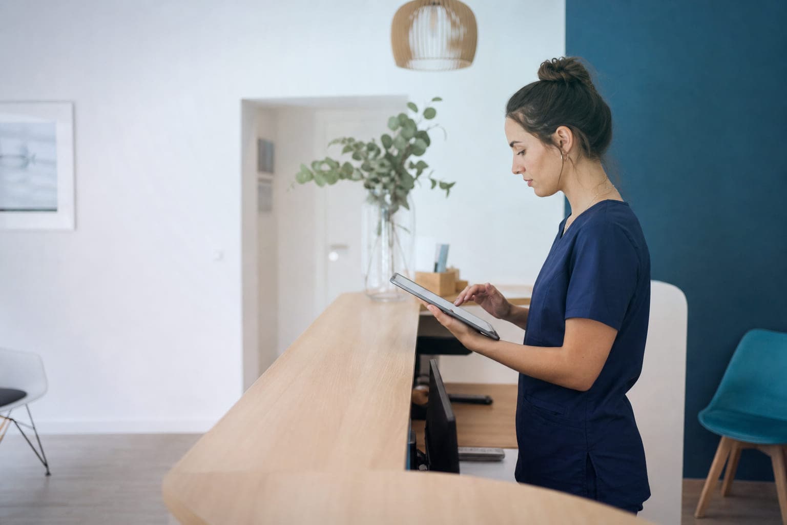 La recepcionista de una clínica dental revisa en una tablet las reseñas recientes del centro.